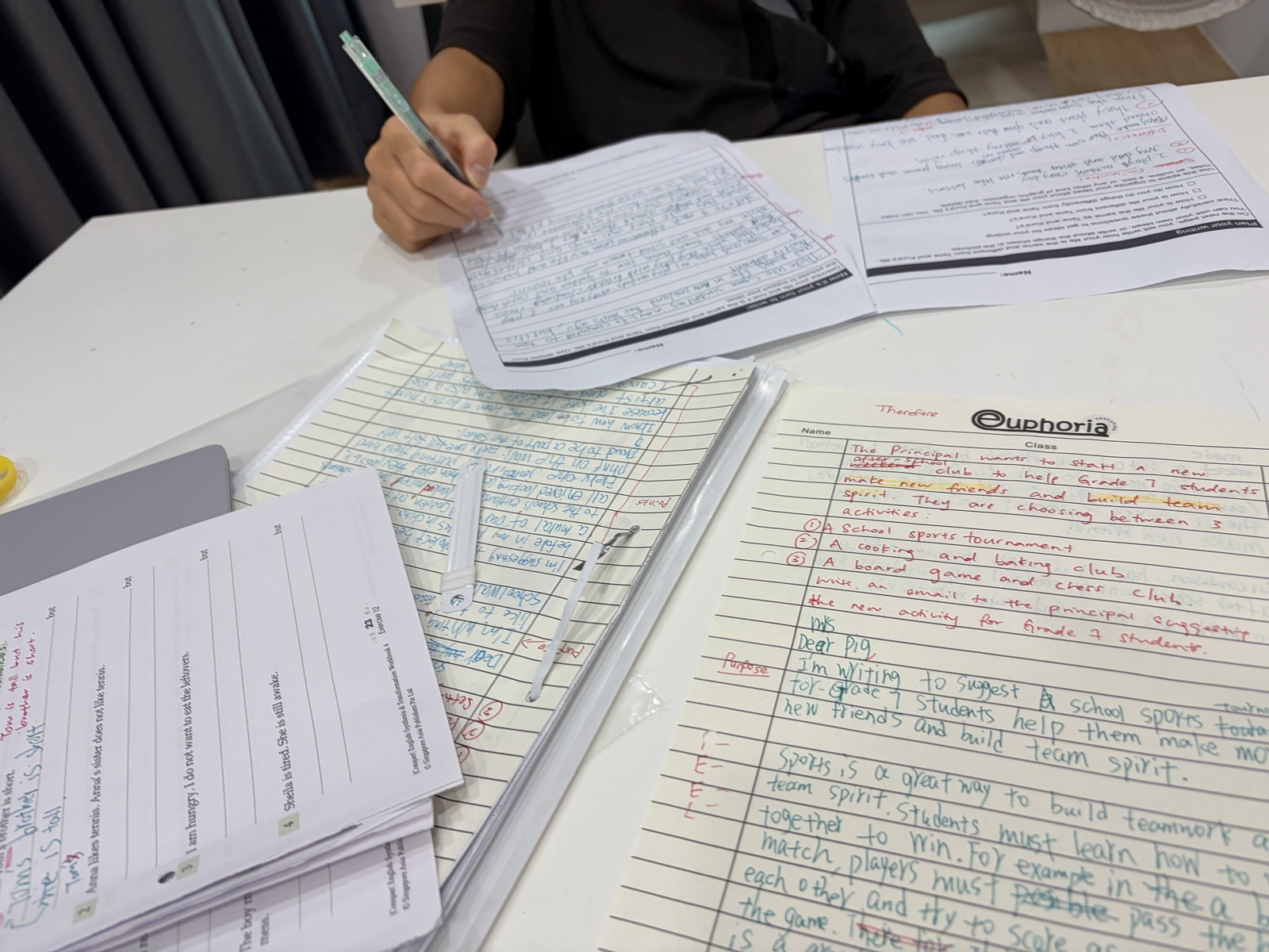 A pupil working on extended writing, with annotated drafts and planning notes on the table